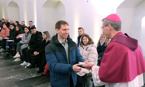 Jannik Heroldt überreicht Bischof Heiner Wilmer bei der Feier der Zusage in der Hildesheimer Seminarkirche das Empfehlungsschreiben seiner Gemeinde für die Taufe. 