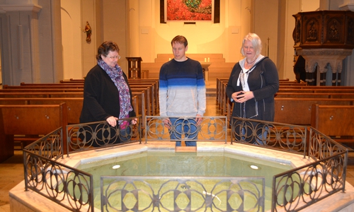In diesen Taufbrunnen wird Jannik Heroldt (Mitte) in der Osternacht steigen. An seiner Seite Gemeindereferentin Dietlinde Schulze (li.) und Katechumenatsbegleiterin Uta Maria Pfeiffer. 