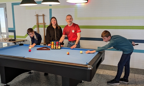 Sozialarbeiterin Hanna Pelter erhält die Poolbillardkugeln und das dazu gehörende Holzdreieck von Tobias Dahnke, Abteilungsleiter und Trainer der Sparte Billard beim MTV Goslar. Jonas (li.) und Lennart (re.) sind die beiden Teilnehmer des Workshops im Rahmen des Osterferienpasses.