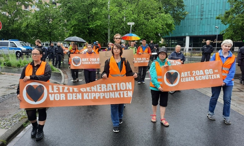 Die Protestler der Letzten Generation marschierten unter Aufsicht der Polizei durch die vom Unwetter gebeutelte Stadt.