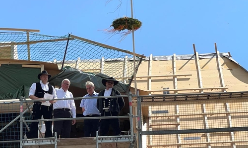 „Mit Gunst und Verlaub“ spricht Malte Sucker seinen umfangreichen Richtspruch. Am Ende dieser festlichen „Weihe“ steht ein Segensspruch für Haus und Menschen. Als Vorstandsmitglied darf Werner Schilli (2. v. links) dann noch den letzten Nagel ins Gebälk schlagen.