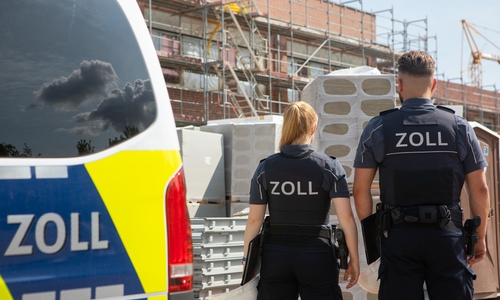 Zollbeamte vor einer Baustelle. 