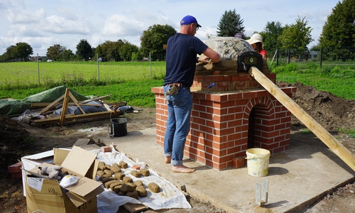Das Herzstück des Ofens, die Kuppel, wird aus Grünlingen aufgemauert. Nach der Fertigstellung erhält der Lehmbackofen einen Regenschutz.