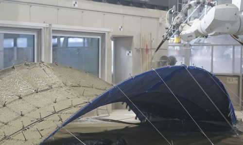 Während der Herstellung eines Demonstrators mit dem sogenannten Shotcrete-Verfahren. Für die Form wird das Knitcrete-Verfahren genutzt, bei dem die zu besprühende Brücke aus technischen Garnen gestrickt wird.