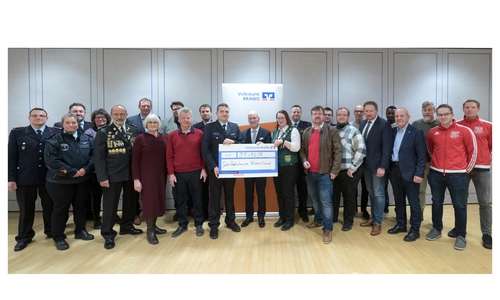 Stefan Honrath von der Volksbank BRAWO (Bildmitte) überreicht einen symbolischen Spendenscheck an 19 gemeinnützige Vereine und Institutionen aus dem Peiner Land.