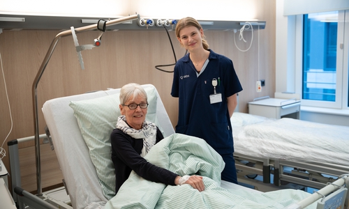 Patientin Juliane Schild ist sicher in ihrem neuen Zimmer im Neubau Ost angekommen. Pflegefachkraft Emma Schulz begrüßt sie in den neuen Räumlichkeiten.