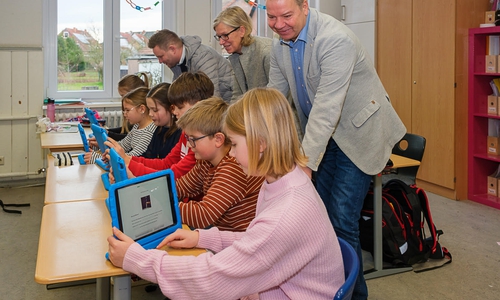 Jens Hanschke (vorn), Annegret Otte und Dennis Heinze lassen sich von den Schülern ihre iPads zeigen. Die blauen Schutzhüllen dienen gleichzeitig als Aussteller für die Geräte. 