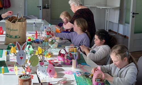 Kinder basteln verschiedene Oster-Dekorationen mit Freiwilligen.