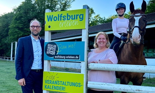 Jens Hofschröer, Wirtschaftsdezernent und Geschäftsführer der Wolfsburg Wirtschaft und Marketing GmbH, Mirka Blischke, Vorstandsvorsitzende des Reit- und Fahrvereins Wolfsburg e. V., und Reitschülerin Belissa neben dem Sprung im Wolfsburg erleben-Design.