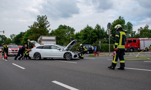 Mit vereinten Kräften wird eins der Unfallfahrzeuge von der Bundesstraße geschoben.