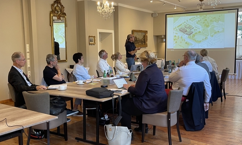 Erster Stadtrat Dirk Becker (stehend) präsentiert vor dem Vorstand des VGT die Planungen zur Stadthalle (links neben ihm Oberbürgermeisterin Urte Schwerdtner und VGT-Präsident Ansgar Staudinger).