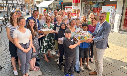 Wirtschaftsdezernent Gerold Leppa (vorne rechts) und Torsten Glaser, Leiter des Regionales Landesamt für Schule und Bildung Braunschweig, übergaben die Präsentkörbe an Schülerinnen und Schüler der Fairtrade AG am Gymnasium Ricarda-Huch-Schule. Im Hintergrund das von ihnen gestaltete Schaufenster der Tourist-Info (Kleine Burg 14).