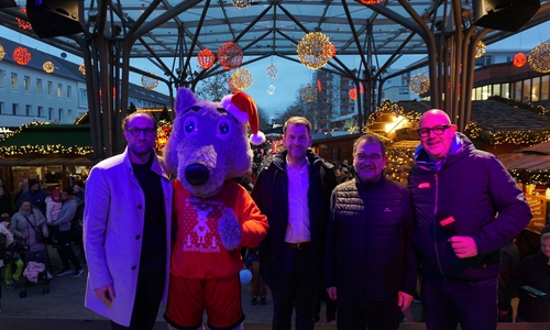 Jens Hofschröer (WMG-Geschäftsführer und Wirtschaftsdezernent), WMG-Maskottchen Lukas Lupino, Oberbürgermeister Dennis Weilmann, Sabah Enversen (stellv. Aufsichtsratsvorsitzender der WMG) und Moderator Dirk Wöhler auf der Wolfsburger Weihnachtsmarktbühne