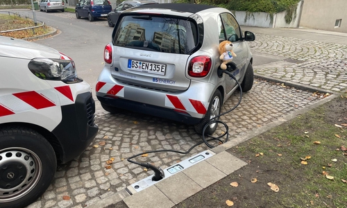 Der Ladevorgang eines Elektrofahrzeugs über den Bordstein.