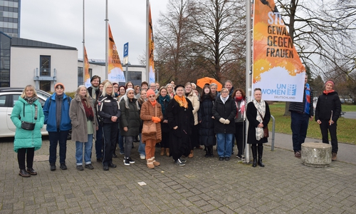 Gruppenbild auf dem Rathausvorplatz beim Hissen der orangen Flagge.