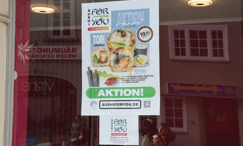 Ein Plakat weist auf die Eröffnung des Sushi-Ladens in der Breiten Herzogstraße hin.