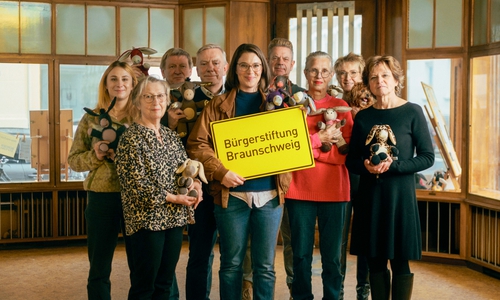 Maria Meibohm (mit Schild, Buchhandlung Graff) steht gemeinsam mit Ehrenamtlichen der Bürgerstiftung Bürgerstiftung im zukünftigen MitMachEck der Stiftung. In den Händen halten die Ehrenamtlichen selbstgenähte Esel, die das Projekt „LEsel unterwegs – Die Rucksackbibliothek“ unterstützen.