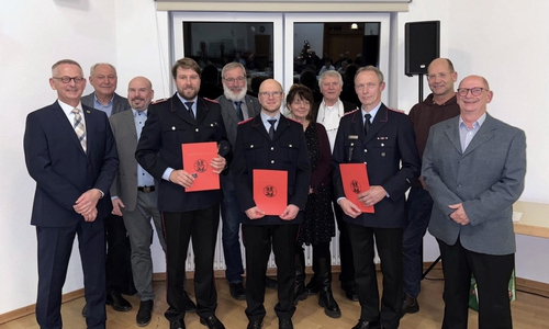 Dirk Neumann, ganz links, mit den Feuerwehrmännern (v. l.) Kevin Müller, Alexander Jacob und Peter Thiele, eingerahmt von Rats- und Verwaltungsmitgliedern.