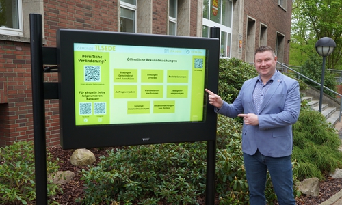 Bürgermeister Nils Neuhäuser, genannt Holtbrügge, vor dem neuen digitalen Info- Monitor.