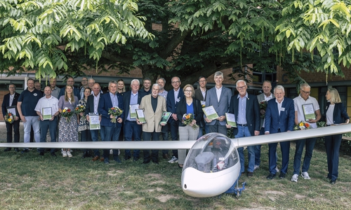 Die Vertreter der 14 bestplatzierten Vereinschronisten stellten sich am Segelflugzeug des vormaligen Siegers zum Gruppenfoto auf.