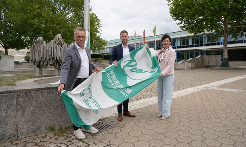 Oberbürgermeister Dennis Weilmann (Mitte) hisst gemeinsam mit Andreas Klaffehn und Immacolata Glosemeyer die Mayors for Peace-Flagge. 