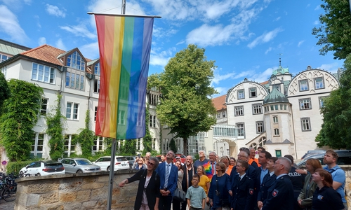 Erster Kreisrat Dominik Meyer zu Schlochtern, Vertreterinnen und Vertreter des Queeren Netzwerks Gifhorn und zahlreiche Gäste hissten die Regenbogenflagge vor dem Schloss Gifhorn.