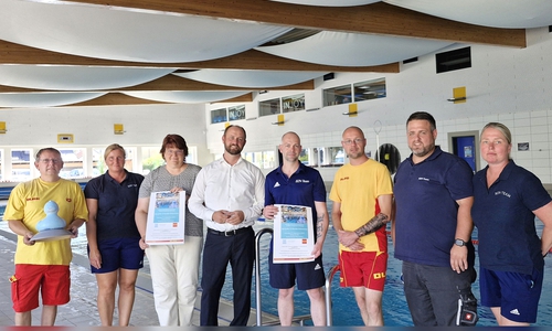 Bürgermeister Malte Schneider (4. v. li.), Badleiterin Frauke Hilal (3. v. li) und der Vorsitzende der DLRG-Ortsgruppe Schöningen Enno Deuter (3. v. re.) freuen sich mit dem Organisationsteam auf das dritte 12-Stunden-Schwimmen.