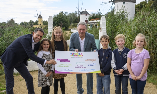 Der niedersächsische Ministerpräsident Olaf Lies (links) wird gemeinsam von Thomas Fast, Vorstandsvorsitzender der Volksbank BRAWO Stiftung und langjähriger Botschafter von United Kids Foundations, und Kindern des Netzwerks im Gifhorner Mühlenmuseum als neuer Schirmherr begrüßt.