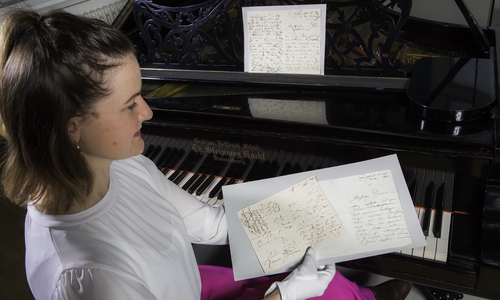 Dr. Antje Becker mit einer Auswahl an Clara Schumann-Autographen am Flügel der Pianistin.