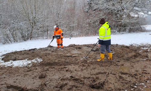 Fachleute bei der Sondierung des ausgehobenen Teichschlamms auf der Wiese.