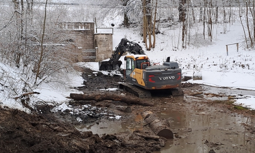 Bagger heben Schlamm aus dem Teich