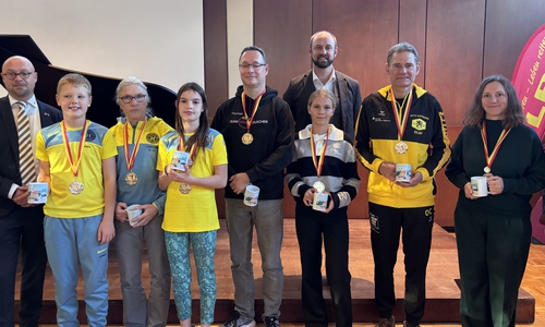 Enno Deuter, Vorsitzender der DLRG-Ortsgruppe Schöningen, und Bürgermeister Malte Schneider (2. Reihe) mit den Champions des 12-Stunden-Schwimmens 2026. 