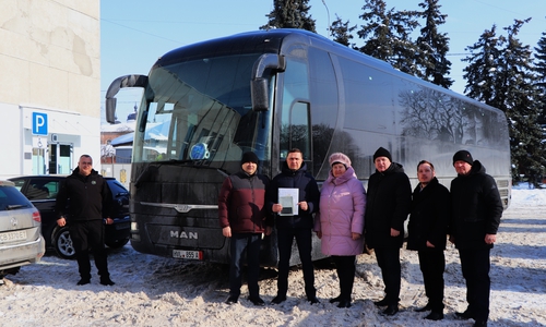 Vasyl Holovachko (links), Fahrer des Reisebus, und Oleksandr Kodola (Dritter von links), Bürgermeister der Stadt Nischyn, bei der Übergabe des Busses.