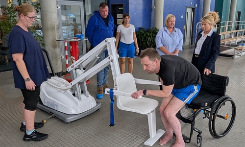 Premiere im Aquantic: Björn Lehrke-Ahrens nimmt im Beisein von Oberbürgermeisterin Urte Schwerdtner (v. re.), Andrea Simon, Behindertenbeauftragte der Stadt Goslar, und Meik Erbrecht (2. v. li.), Technischer Leiter des Bäderbetriebs, sowie zwei Schwimmmeisterinnen auf dem neuen Schwimmbadlifter Platz.