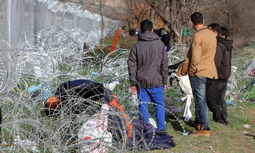 Flüchtlinge auf der Balkanroute vor einem Grenzzaun (Archiv)