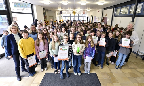 Die Klasse 4b mit dem Team-Namen „Die Gewinnerwaschbären“ freuen sich über Pokal und Urkunden des step BRAWO-Schrittewettbewerbs, die sie von Claudia Kayser (li.), interimsmäßige Direktionsleiterin Gifhorn der Volksbank BRAWO, erhalten haben. 