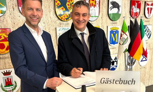 Im Beisein von Oberbürgermeister Dennis Weilmann trägt sich Generalkonsul Piero Vaira (rechts) in das Gästebuch der Stadt ein.
