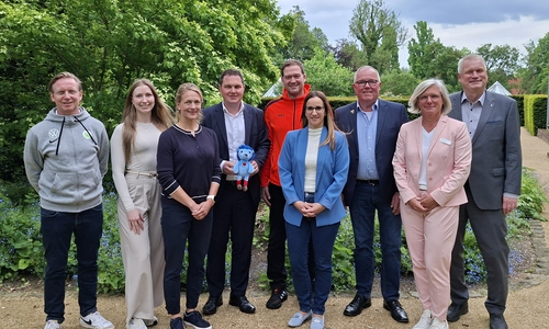 Bei der Vorstellung der Studienergebnisse (von links): Roy Präger vom VfL Wolfsburg, Marleen Stridde von der Audi BKK, Studienkoordinatorin Melanie Lemke vom Universitätsklinikum Hamburg-Eppendorf, Landrat Philipp Raulfs, Miroslav Jenka, Trainer bei den Grizzlys, Projektleiterin Janine Ahrends von der Gesundheitsförderung und Prävention des Landkreises Gifhorn, Norbert Blyszcz, Vorstandsmitglied der Young Grizzlys Wolfsburg, Nele Westphal, Fachbereichsleiterin Kinder, Jugend und Familie beim Kreisverband Gifhorn des Deutschen Roten Kreuzes, und Kreisrat und Gesundheitsdezernent Rolf Amelsberg. Landrat Philipp Raulfs hält das Maskottchen Tobi des Bewegungsprojekts in den Händen. 