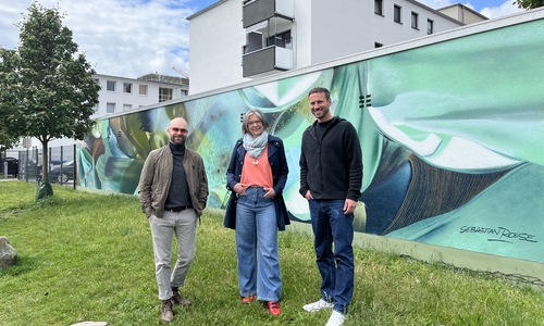v. l. Künstler Sebastian Roese, Initiatorin und Antragstellerin Madeleine Stellmacher sowie Florian Martin (Citymanager der WMG) vor dem neuen Wandbild "Garten 35A" in der Kolpingstraße.