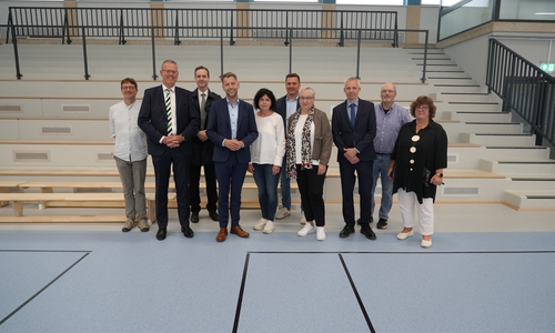 Vertreterinnen und Vertreter aus Verwaltung, Schule und Wolfsburger Schulmodernisierungsgesellschaft bei der Wiedereröffnung der sanierten Dreifeldsporthalle am Schulzentrum Vorsfelde. Mit dabei waren unter anderem Oberbürgermeister Dennis Weilmann (4. v. l.), Stadträtin Iris Bothe (4. v. r.), die Geschäftsführer der Wolfsburger Schulmodernisierungsgesellschaft Christoph Andacht und Marc-Frederik Augath sowie die Schulleitungen des Schulzentrums.
