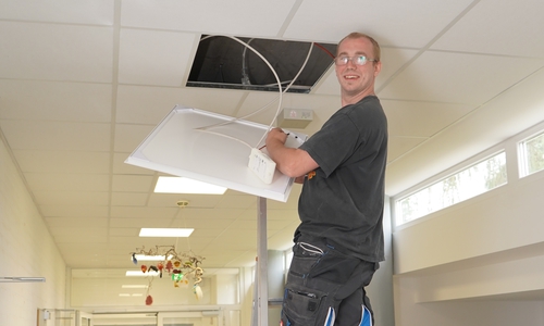 Ein Mitarbeiter des Bauwirtschaftshofs der Gemeinde Ilsede nimmt den Einbau der Beleuchtung in der Grundschule vor.