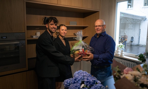 Die Gründer Tim Deichmann und Sina Joost erhalten ein Einzugsgeschenk von Rainer Müller, der bei Garant Gründungen betreut.