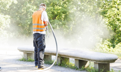 Eine Parkbank wird sandgestrahlt.
