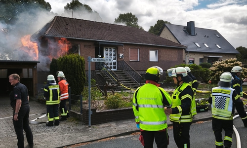 Küche im Vollbrand beim Eintreffen erster Kräfte: Aus beiden Fenstern (links vorn und Seite) schlagen massiv Flammen, Rauch steigt bereits aus dem Dachstuhl.