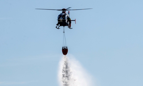 Bei der Übung zur Vegetationsbrandbekämpfung wirft ein Hubschrauber Wasser aus einem sogenannten „Bambi Bucket“ über der vorgesehenen Fläche ab.