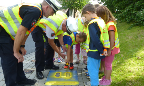 Gunter Pramann (hinten) und Ralf Buchmeier unterstützen die Kinder beim Aufsprühen der gelben Füße. 
Foto: Timo Pischke\DRK Kreisverband Goslar