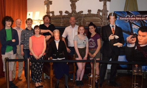 Begeistert von der James-Bond-Ausstellung posieren die drei Schüler mit Bürgermeister Mahnkopf (Mitte) und ihren begleitenden Lehrkräften neben der Queen und Pierce Brosnan. Fotos: Stadt Goslar 