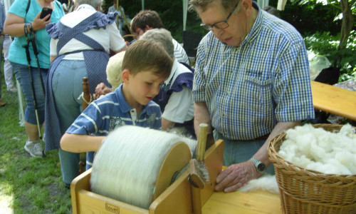 Mit der Kardiermaschine bürsten die Kinder die Wolle fein. Foto: Förderkreis Heimathaus Alte Mühle Schladen e.V. 