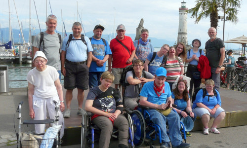 Eine Reisegruppe posiert am Bodensee. Im Hintergrund ist der
Leuchtturm von Lindau. Foto: Privat