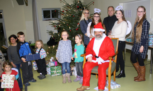 Landrat Gerhard Radeck mit seinen Helferinnen, dem Weihnachtsmann und einigen Kindern bei der Bescherung. Foto: Lebenshilfe